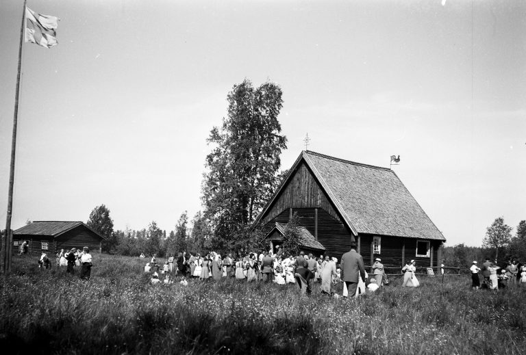 Turkansaaren kirkon edessä juhlakansaa ja suomen lippu. Vanha mustavalkoinen valokuva.
